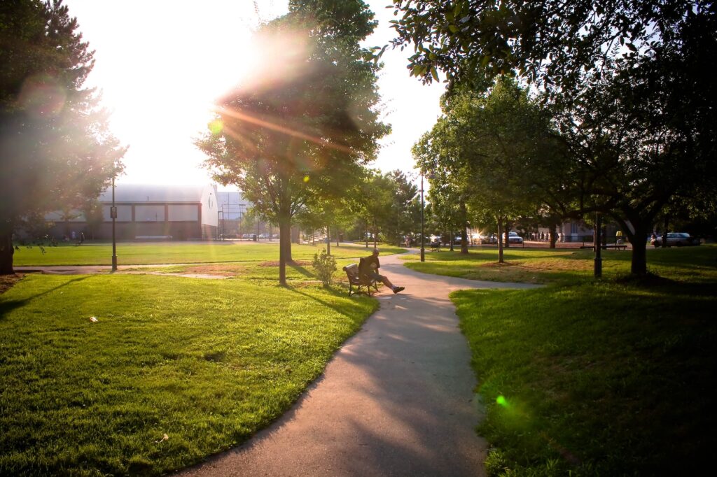 a man is sitting on a bench in the evening square in the background light of a park path